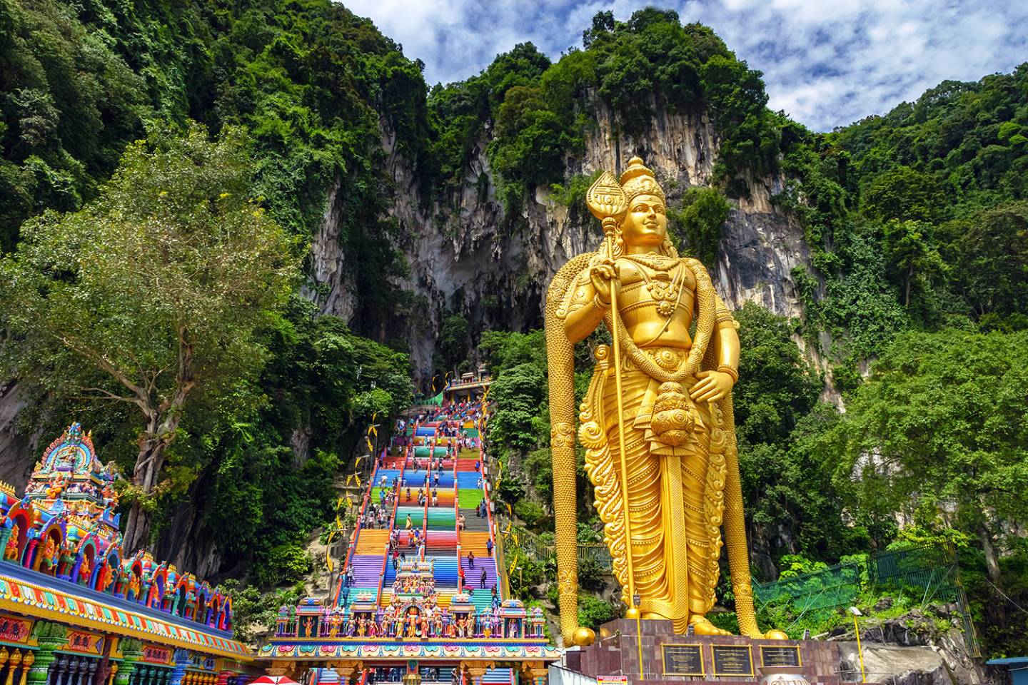 large golden statue in front of steps to cave