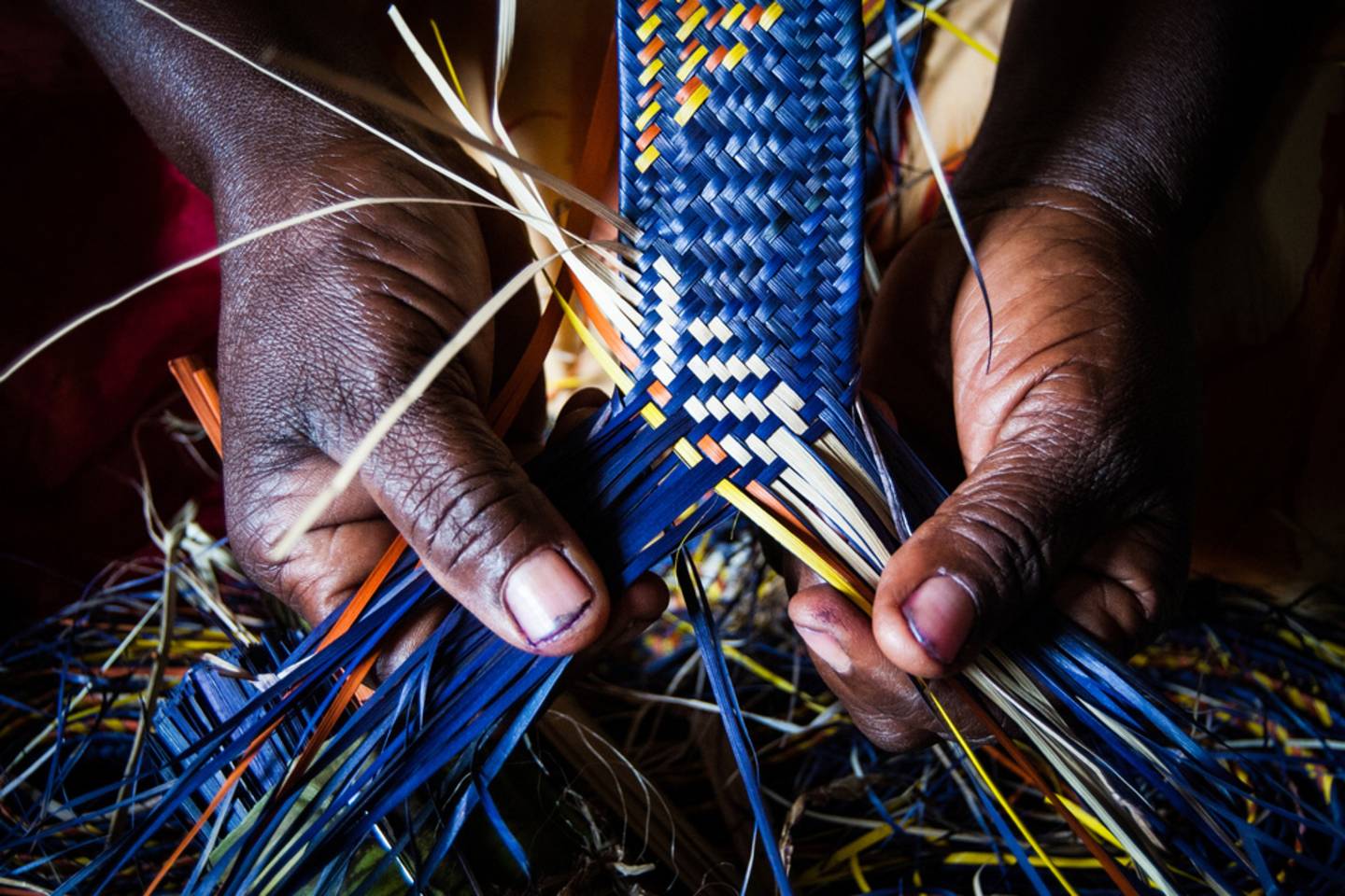 hands weaving a mat